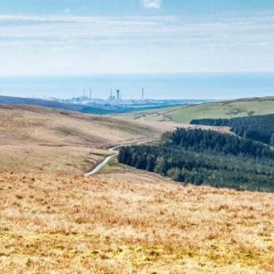 Grassy hills with industrial facility in the background